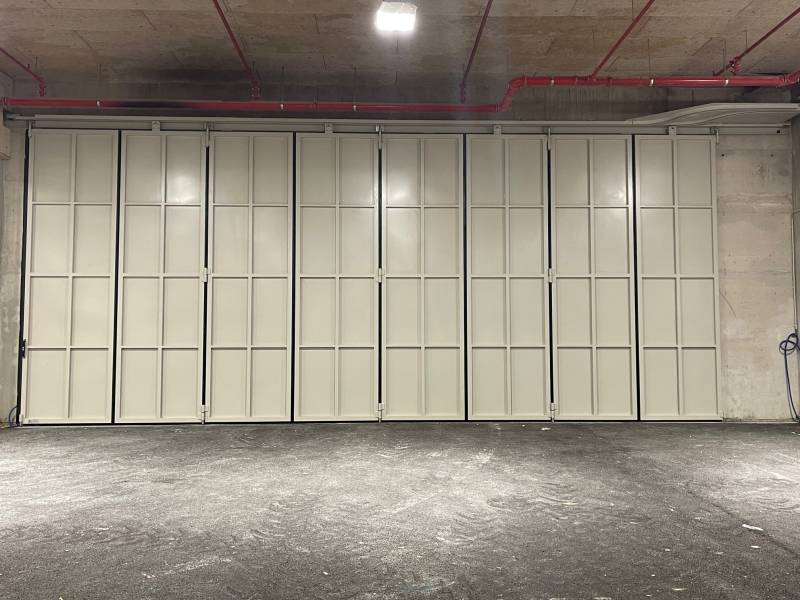 Vue d'ensemble d'une porte accordéon installée en position ouverte, maximisant l'espace dans un garage d'entreprise à Monaco